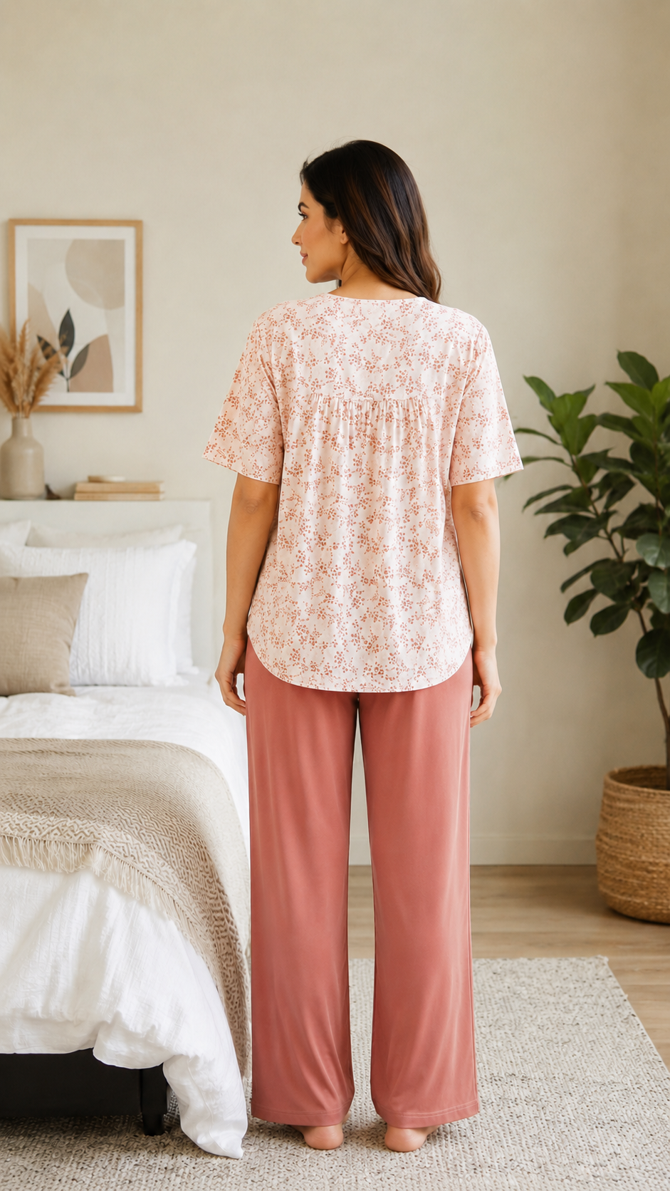 Woman wearing a pink lace top and pants in a bedroom setting.

