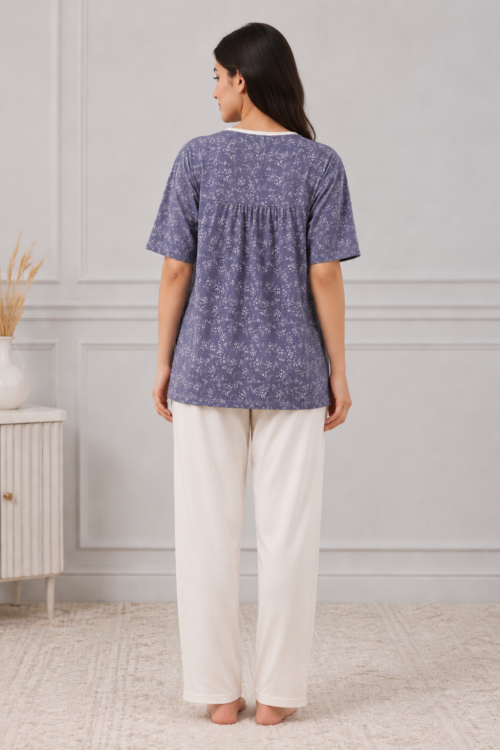 Woman wearing a blue patterned top and white pants 

