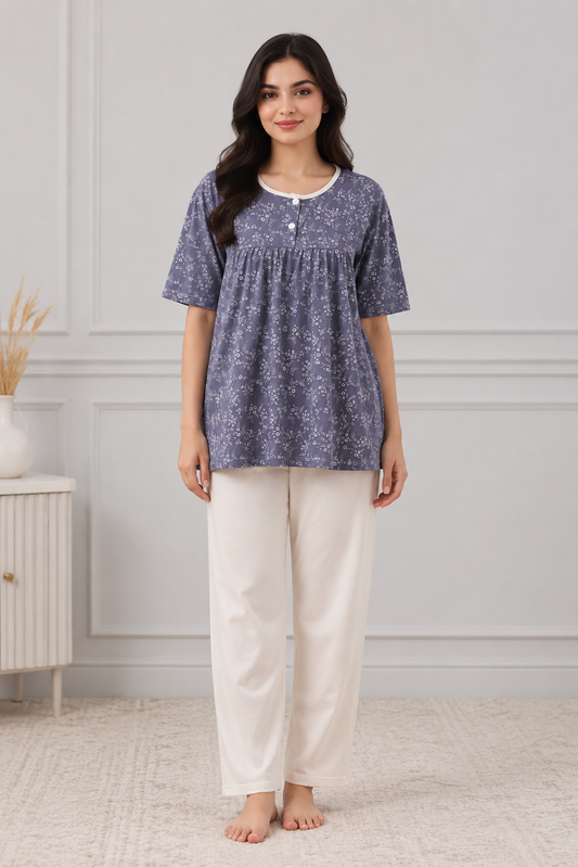 Woman wearing a blue floral top and white pants in a room with a neutral background

