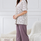 Woman wearing a floral top and purple pants 