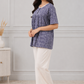 Woman wearing a blue patterned top and white pants